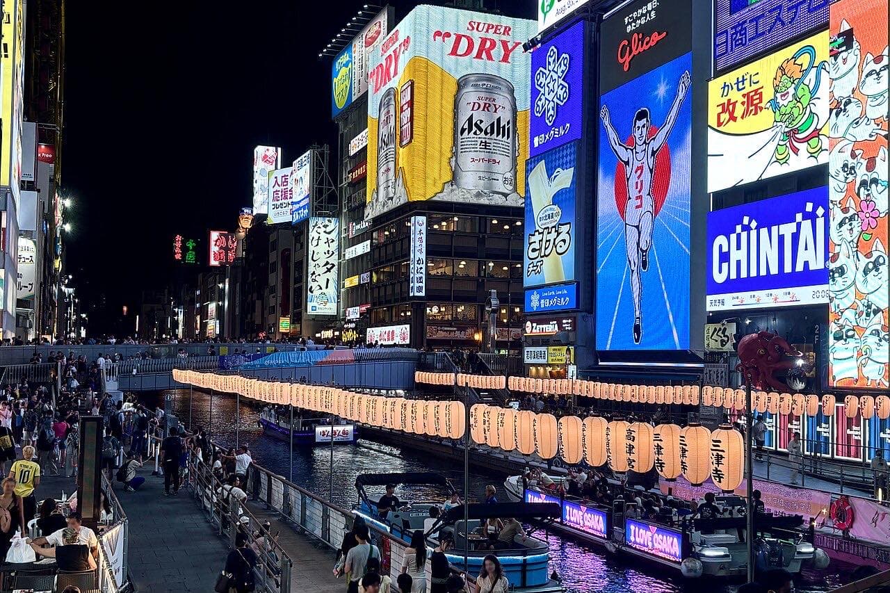 Illuminated signs beside the Dotonbori canal in Osaka at night.
