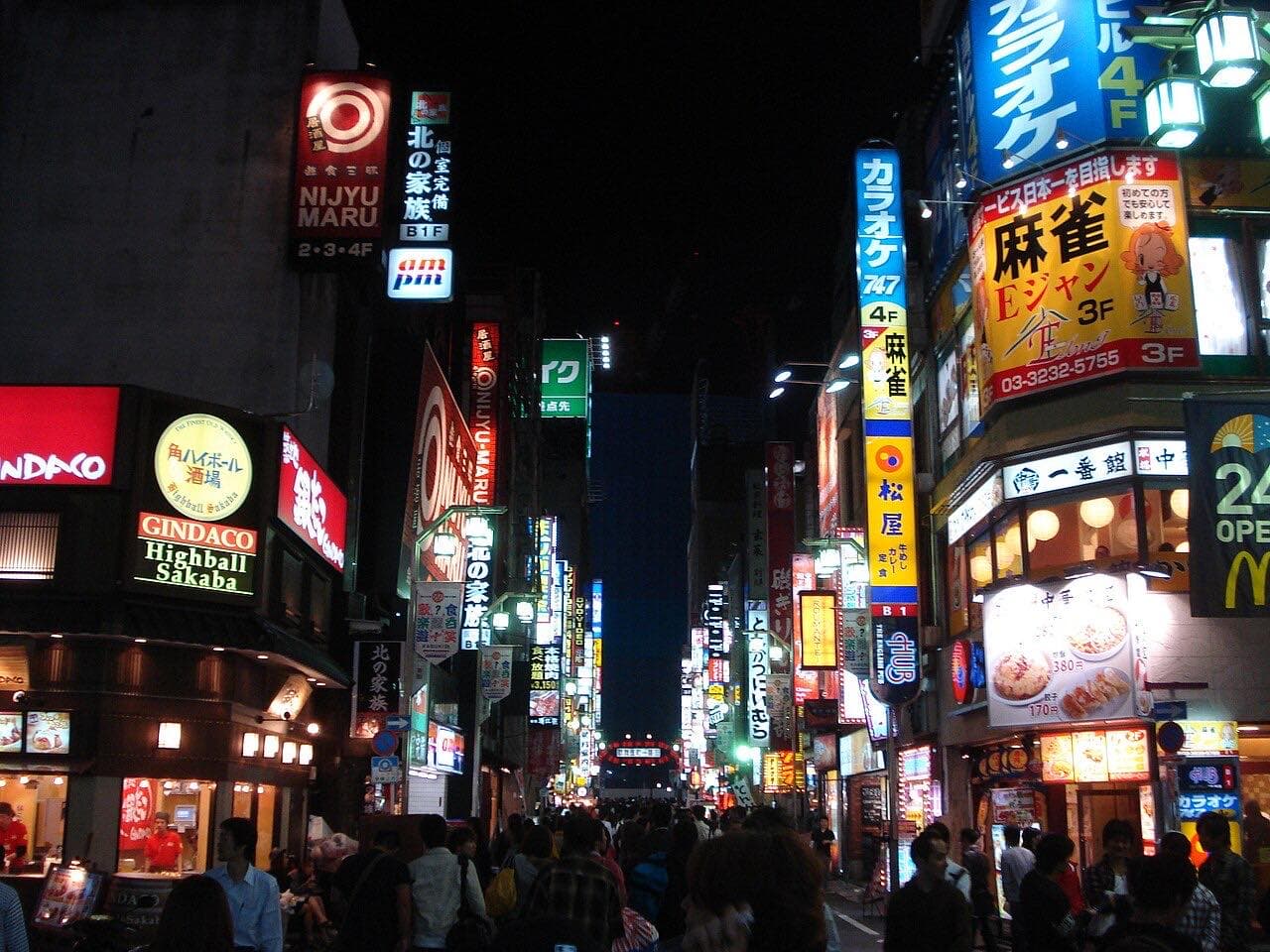 An illuminated street in Shinjuku, Tokyo, after dark.